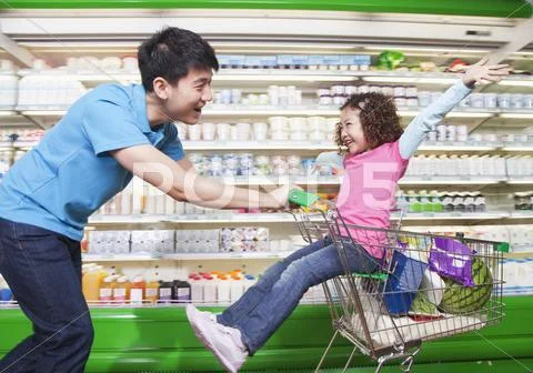 Father Pushing Daughter in Shopping Cart Inside Supermarket Stock Photos