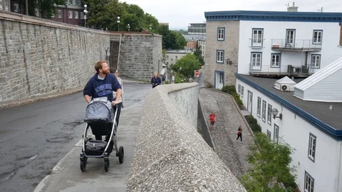 Father pushing a stroller uphill in quebec city Stock Footage 92226730