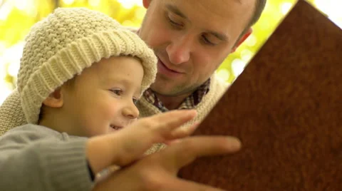 Father reading book to his son in yellow autumn forest Stock Footage 68956335