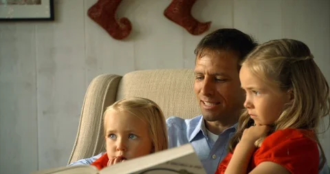 Father reading a book to his two daughters. Vidéo 88377166