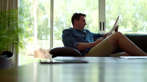 Father reading newspaper while children using digital tablet at home. Stock Footage 64108891