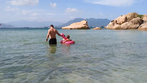 Father riding son on swim ring. Family take fun in clear ocean water. Stock Footage 263096746