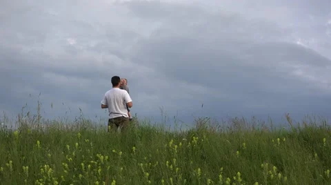 Father rising up his son to dramatic sky, spring hill  Stock Footage 46206731
