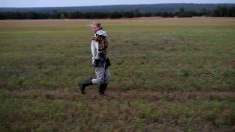 Father running through a field while holding his child in his arms 库存影片 300096903