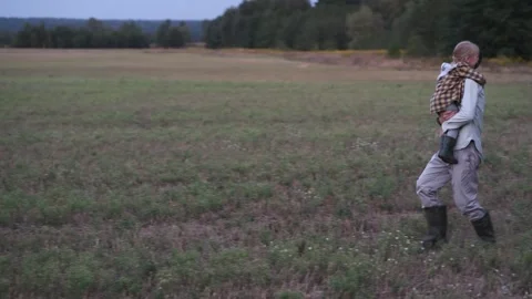 Father running through a field while holding his child in his arms 库存影片 300096994