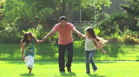 A father runs through an open green field with his two daughters on a sunny day Video stock 33871265