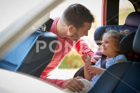 Father Securing Daughter Into Rear Child Seat Before Car Journey Stock Photos