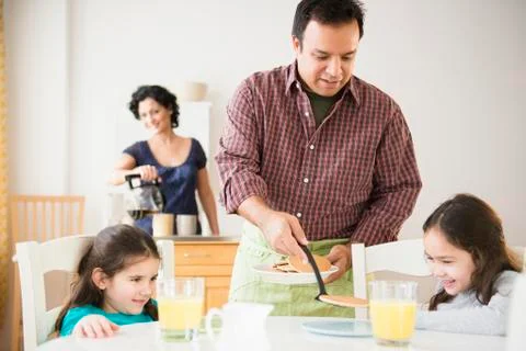 Father serving daughters breakfast at table Stock Photos