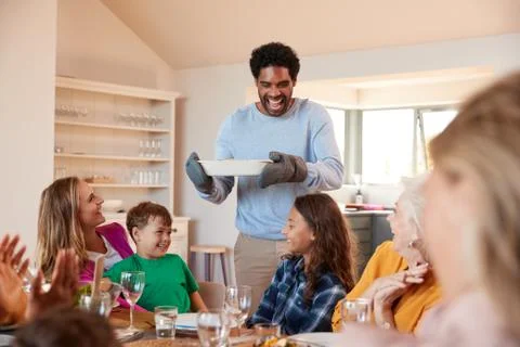 Father Serving Food As Multi-Generation Family Meet For Meal At Home Stock Photos