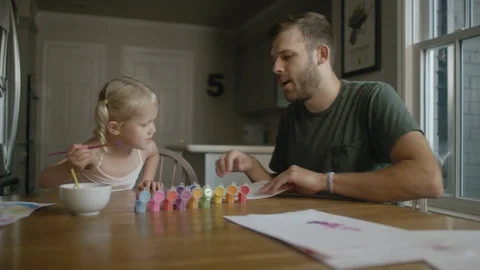 Father sets down a new piece of paper for his daughter that's painting Video stock 114163908