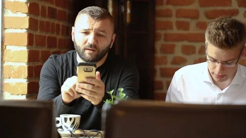 Father showing something on smartphone to his son while sitting in the cafe Stock Footage 80424747