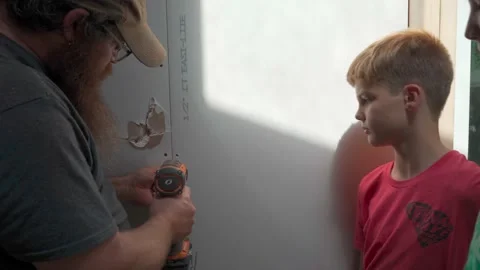 Father showing son how to hang drywall on DIY project Stock Footage 159004232