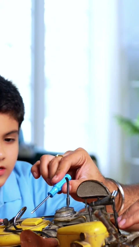 Father shows child how to fix broken toy through hands on learning Stock Footage 342758199