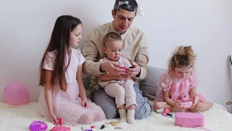 A father sits on a couch with three children at a birthday gathering at home. Stockbeeldmateriaal 336462681
