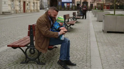Father sitting on the bench and dressing shoes  Stock Footage 60962714
