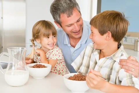 Father sitting with children as they eat breakfast Stock Photos