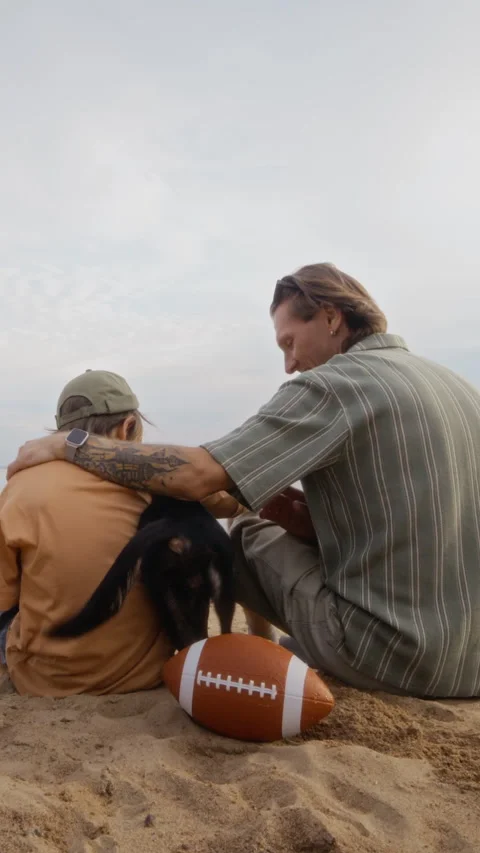 Father Sitting on Sandy Beach with Son Playing with Pet Dog Stock Footage 340264512