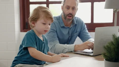 Father sitting at work using tablet while son drawing and painting Stock Footage 236876478