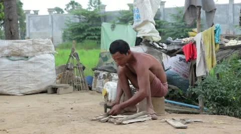 Father in slums preparing fire by cutting wood Stock Footage 12171827