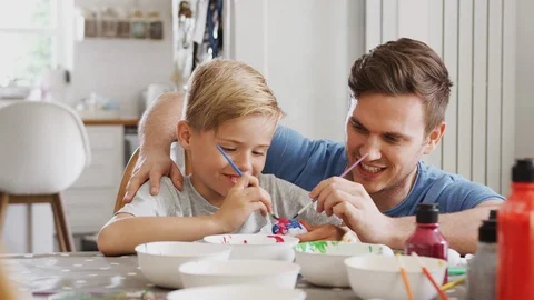 Father With Son Sitting At Table Decorating Eggs For Easter At Home Stock Footage 114308488