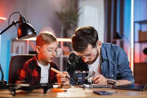 Father with son using soldering iron for fixing display card Stock Photos