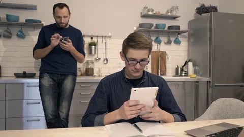 Father with son using tablet and smartphone in kitchen at home Stock Footage 73474082