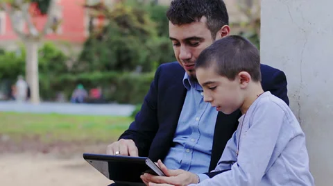 Father to son using tablet computer in the park Stock Footage 32942817