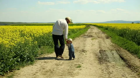 Father with son walking and looking back on a dirt road at the village Stock Footage 63641935