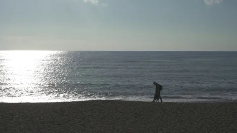 Father &amp; Son walking on yhe beack in backlight situation. Ungraded. Video stock 73260915