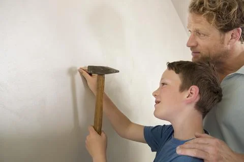 Father son working together hammer wall nail Stock Photos