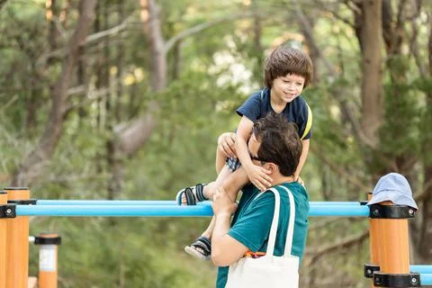 Father taking down his son from sport equipment Stock Photos