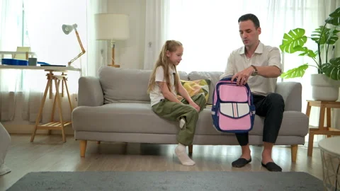 The father talked to his daughter, packed her school supplies in her backpack, Stock Footage 340910476