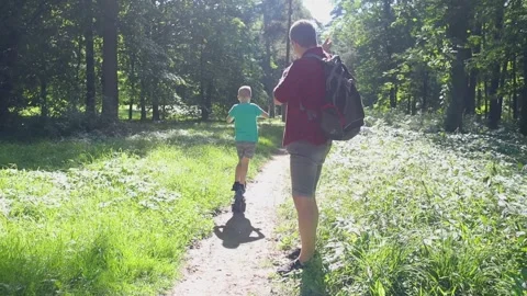 A father teaches his son how to ride an electric scooter. Riding an e-scooter wi Video stock 247360295