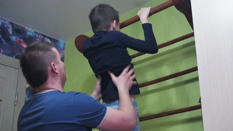The father teaches his son to pull up on the horizontal bar at home. playing Stock Footage 167797115