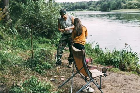 A father teaches his teenage daughter to fish during a family vacation Stock Photos