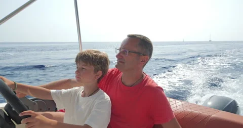 Father teaches son the driving of speed motor boat on the sea Video stock 338017961