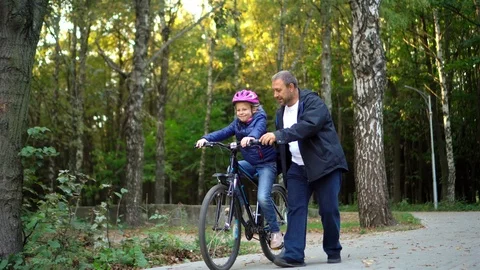 Father teaching daughter to ride bike Stock Video Pond5