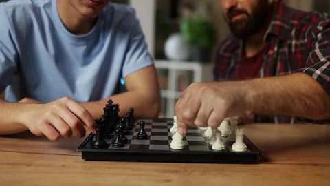 Father teaching his adolescent son to play chess, enjoying board game together Stock Footage 329841548