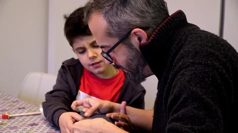 Father teaching his alpha generation son how to wrap Christmas presents Stock Footage 345253298