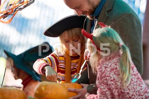 Father teaching his daughters carve a pumpkin Stock Photos
