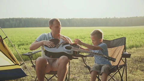 Father teaching his son how to play the guitar in camping. Stock Footage 130602823