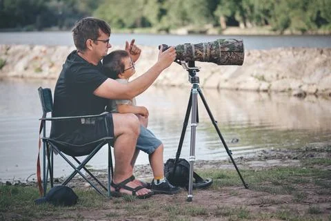 Father teaching his son how to photograph wildlife with a super telephoto len Photos