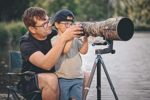 Father teaching his son how to photograph wildlife with a super telephoto len Photos