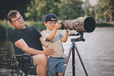 Father teaching his son how to photograph wildlife with a super telephoto len Photos