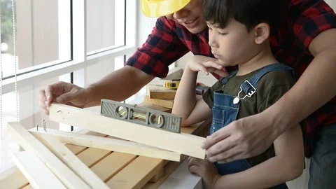 Father teaching his son to use a spirit level on work plank wood. Stock Footage 109119596