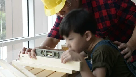 Father teaching his son to use a spirit level on work plank wood. Vidéo 109205978