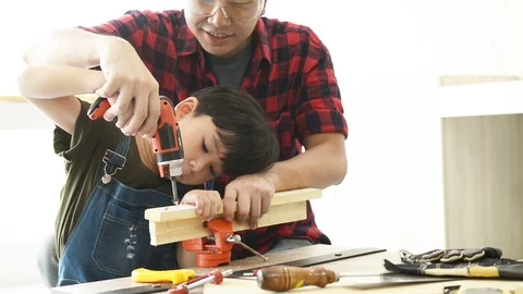 Father teaching his son use electric drill for fasten the wood plank. Stock Footage 114866336
