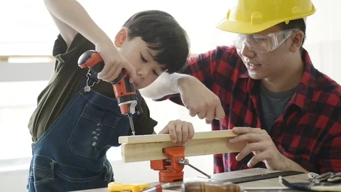 Father teaching his son use electric drill for fasten the wood plank. Stock Footage 114870431