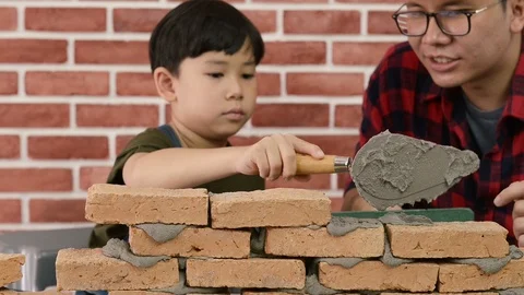 Father teaching his son to use a spirit level and doing masonry. Vidéo 115519217