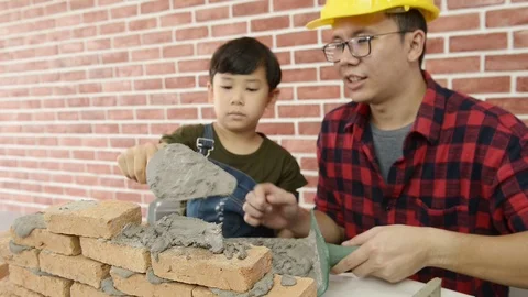 Father teaching his son use trowel and masonry in workshop. Vidéo 115520462